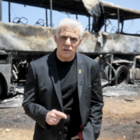Le chef de l'opposition Yaïr Lapid devant un bus touché la veille par un missile balistique iranien, à Herzliya, dans le centre d’Israël, le 18 juin 2025. (Crédit : Capture d'écran d'une vidéo diffusée par Lapid)